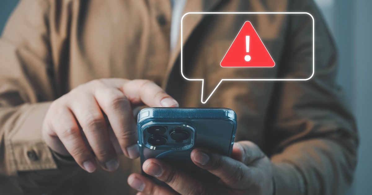 JobScams-Blog Featured Image warehouse worker looking at phone screen checking for fake online job postings
